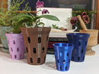 Brown orchid pot with a purple orchid beside purple and blue pot sizes