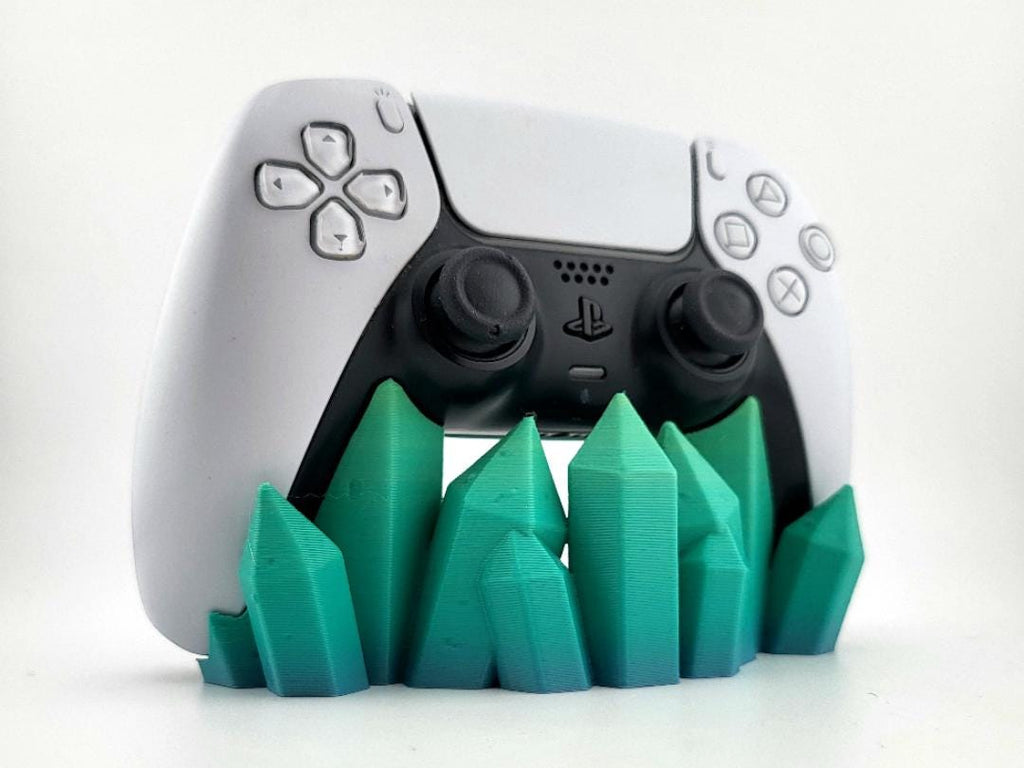 Teal-green crystal-shaped stand holding a PS5 DualSense controller; pictured color example, controller excluded