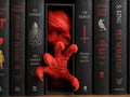 Red demon face and claw emerging from a black book nook between books