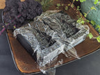 Open Christmas tree butter mold lined with clear plastic wrap on a tray beside decorative greenery.