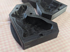 Open black bunny butter mold sections with recessed cavities on pink gingham fabric.