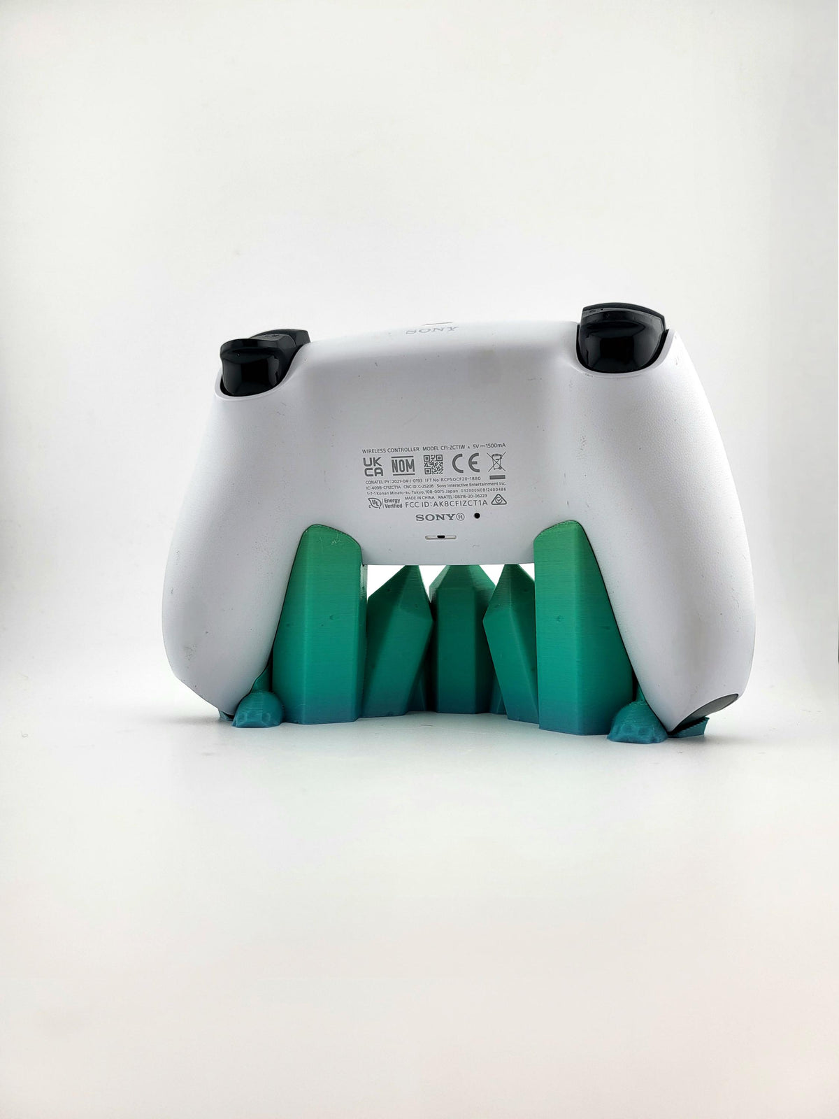 Rear view of PS5 controller on teal-green crystal stand; pictured color example, controller excluded