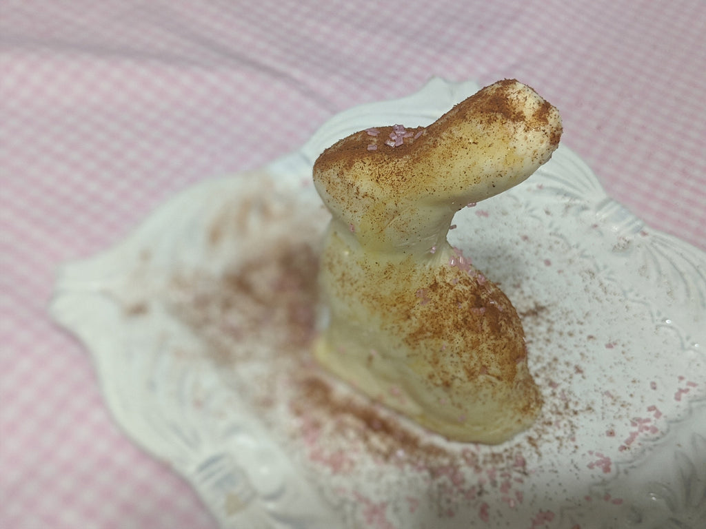 Molded butter figure standing on an ornate white plate dusted with brown powder.