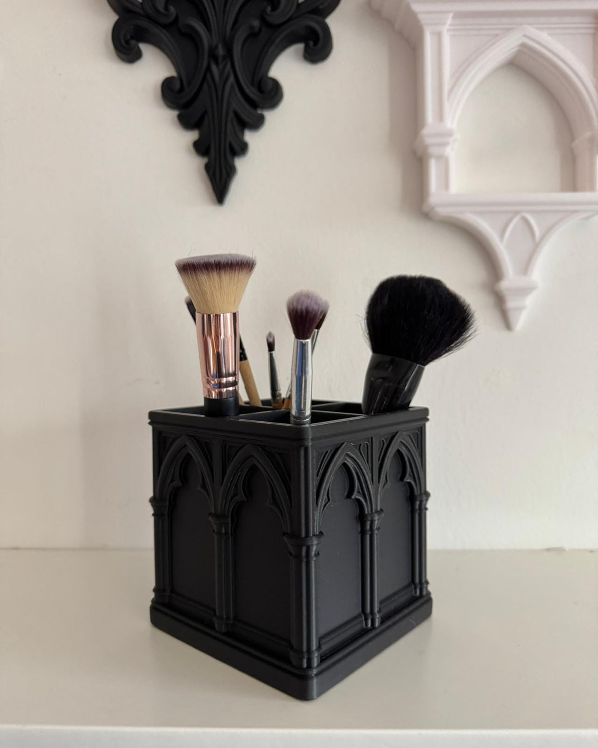 Black Gothic makeup brush organizer with four brushes displayed beneath decorative wall arches