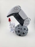 Moon and rocket stand holding a PS5 DualSense controller; controller excluded