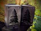 Two Christmas tree butter molds side by side, showing their recessed branch and trunk details.