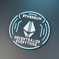 Rendered Ethereum Orbit medallion with cyan-and-white emblem, circuit rings and Decentralize Everything lettering on gray.