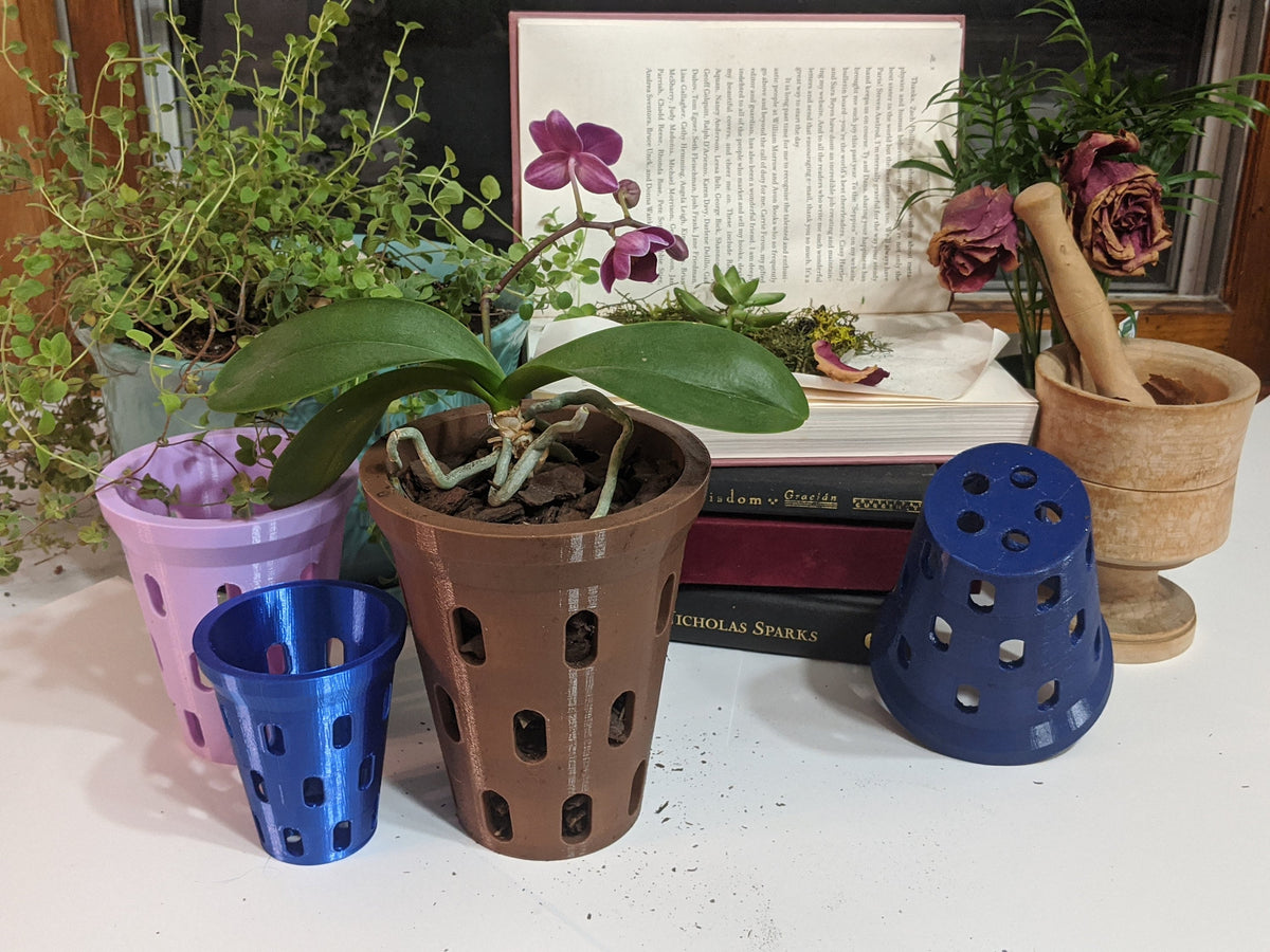 Purple orchid in a brown aerated pot displayed with small blue and purple pots