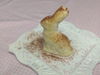 Side view of the molded butter figure standing on an ornate white plate.