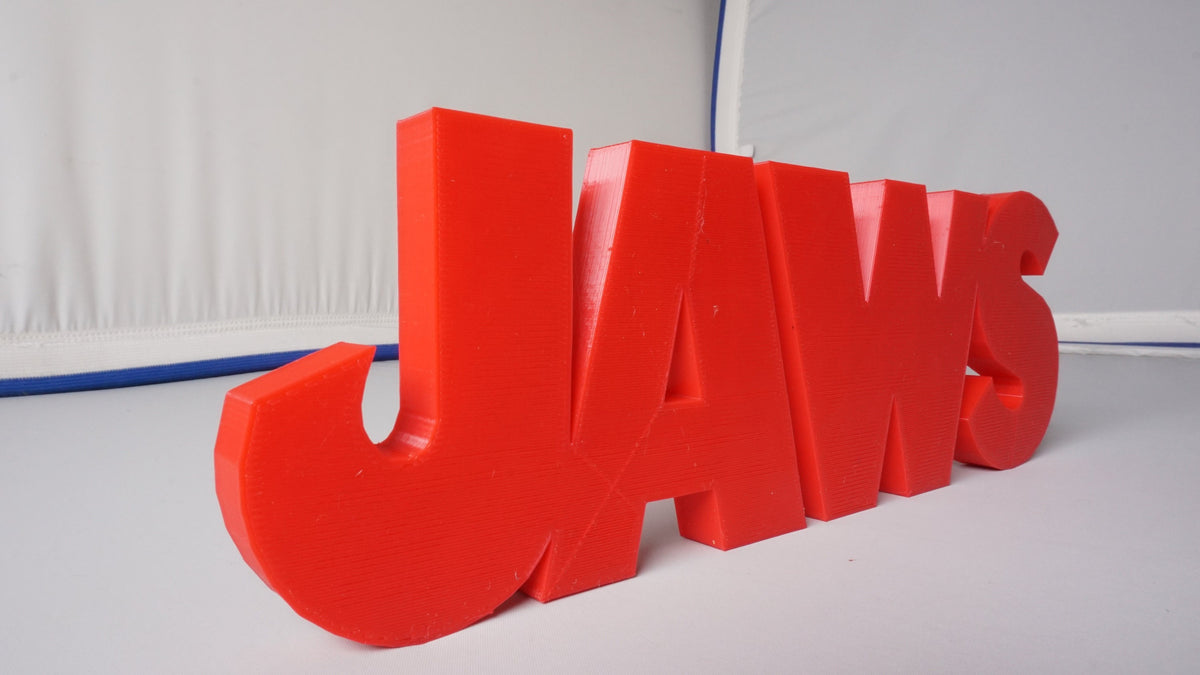 Low left-front view of the red JAWS sign emphasizing the thick J and letters receding to the right.