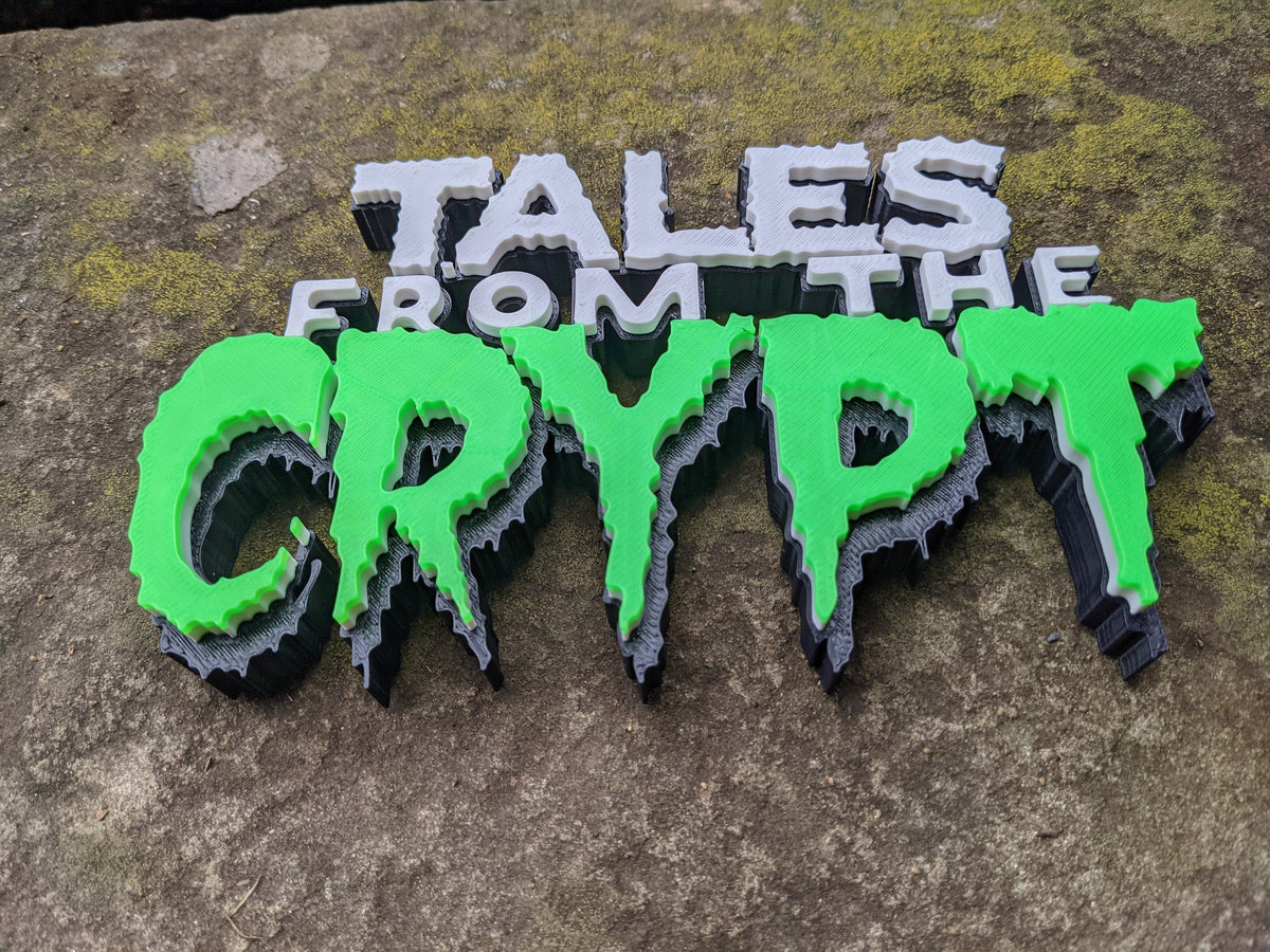Angled view of the Tales from the Crypt sign on textured stone, showing layered lettering and thick dark sides.